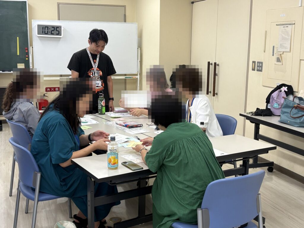 講座の様子。テーブルを囲む受講生と、進行する当社代表 柴田